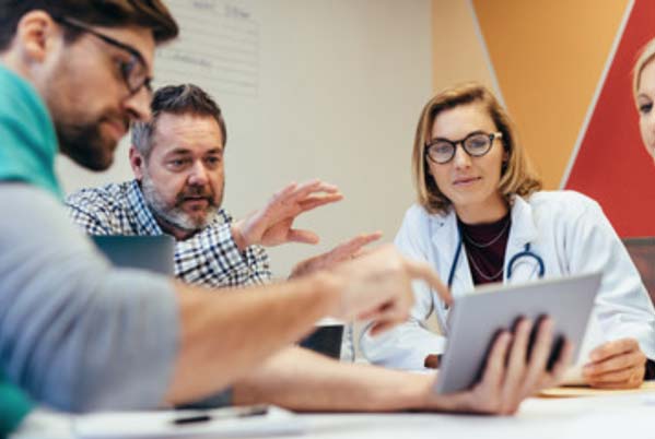 Doctors collaborating around a tablet.